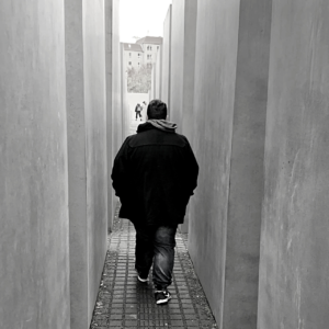 Troy Reid walking away from camera through jewish memorial pillars in Berlin